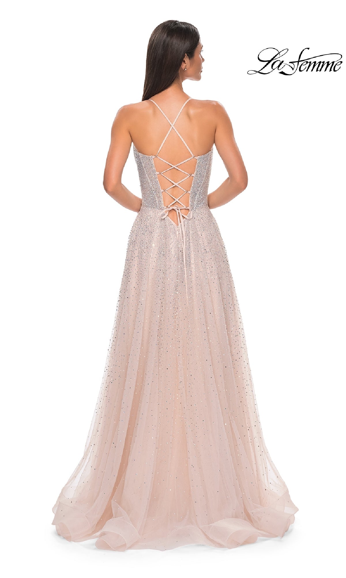A woman faces away in the Lace-Up Beaded Long Prom Ball Gown: La Femme 32725, featuring a pink A-line silhouette, lace-up back, crisscross straps, flowing tulle skirt, and subtle sparkles for added elegance.